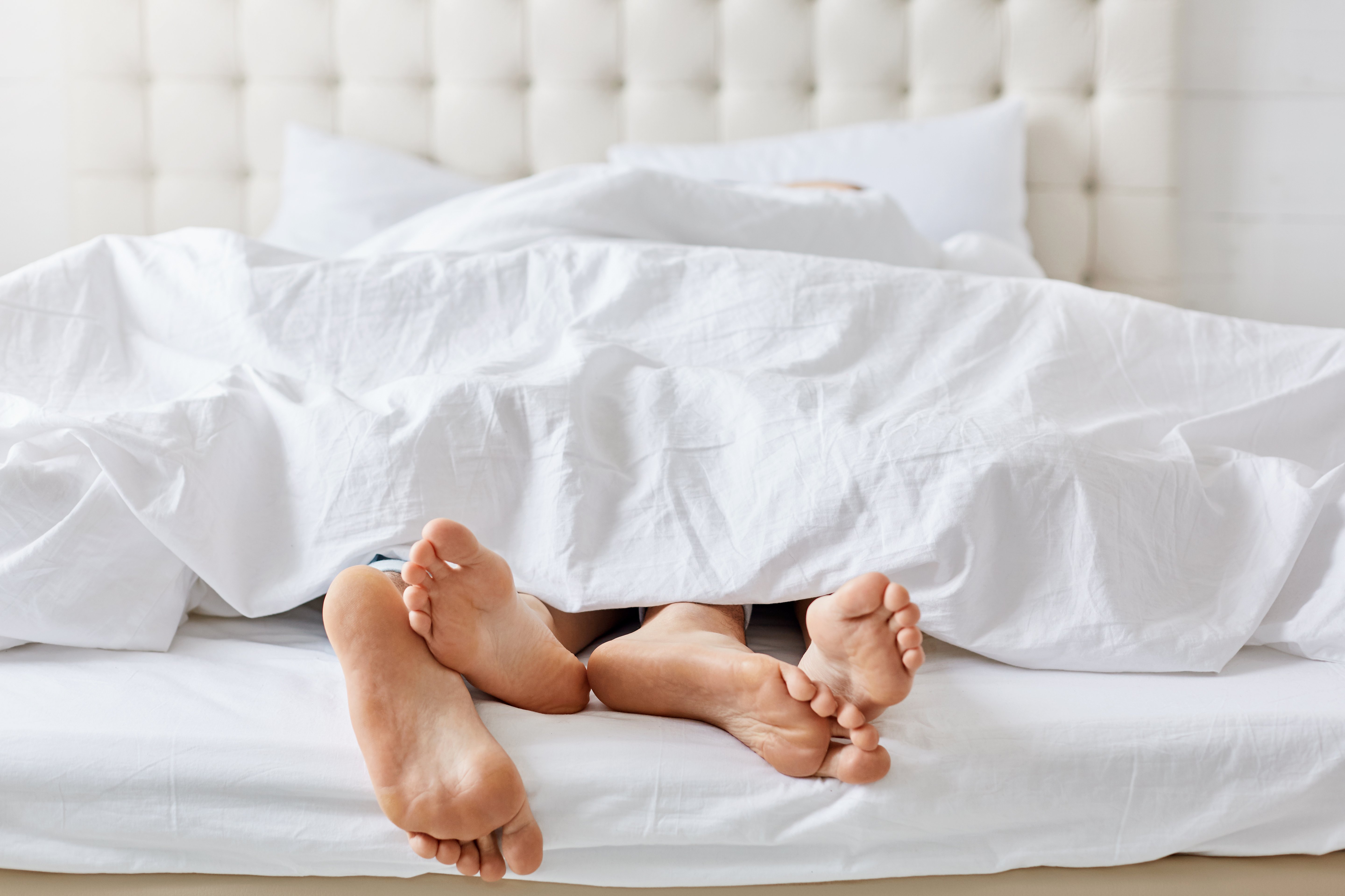 horizontal-shot-feet-couple-white-bedclothes-bed-bedroom